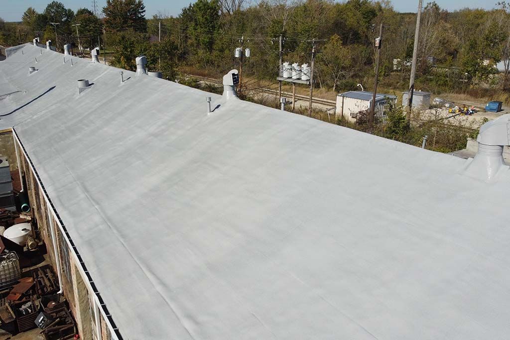 Large white roof in an outdoor industrial area with trees in the background
