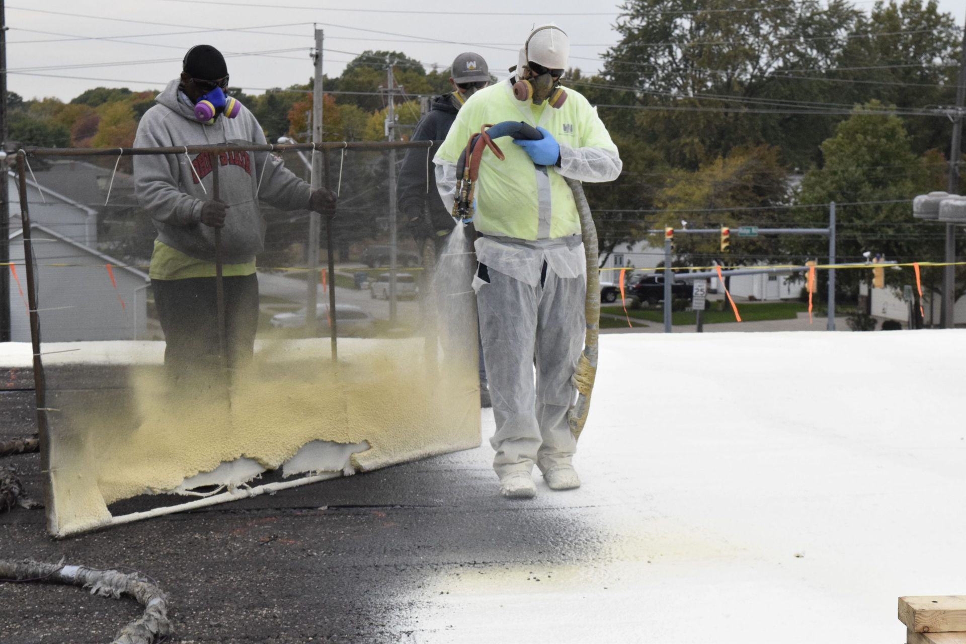 Workers spraying water on a smoking rooftop fire during cleanup and suppression