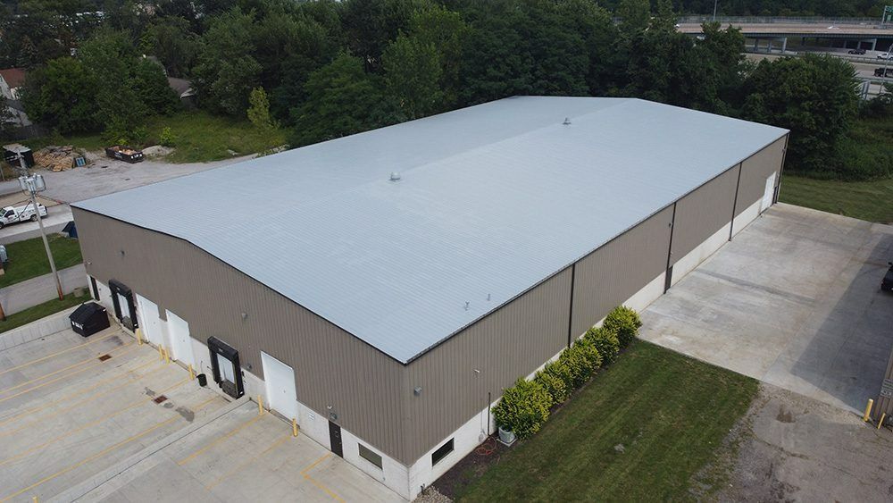Aerial view of a large white-roofed warehouse with beige walls and surrounding paved lot.