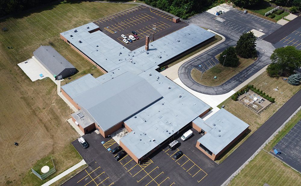 Aerial view of a school building with parking lots and surrounding lawns