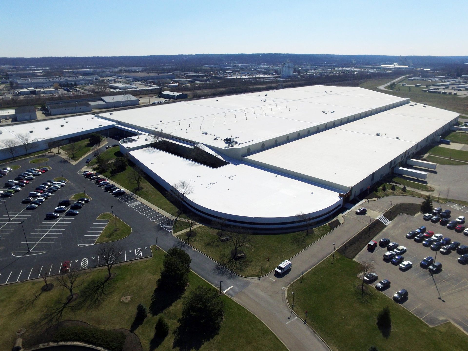 Aerial view of a large white-roofed warehouse with parking lots and surrounding roads.
