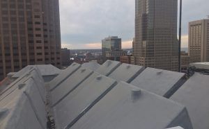 Rooftop with gray metal panels overlooking downtown office buildings at dusk