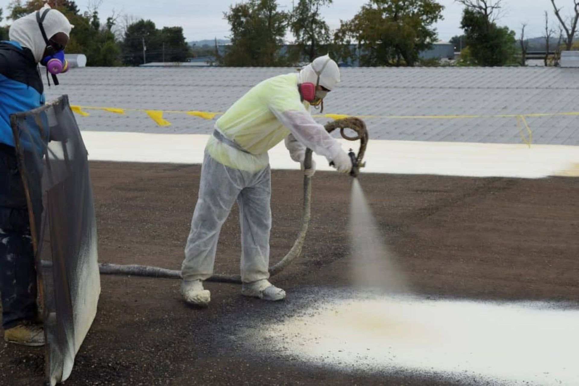 spray foam coming out of a spray gun on a commercial roof