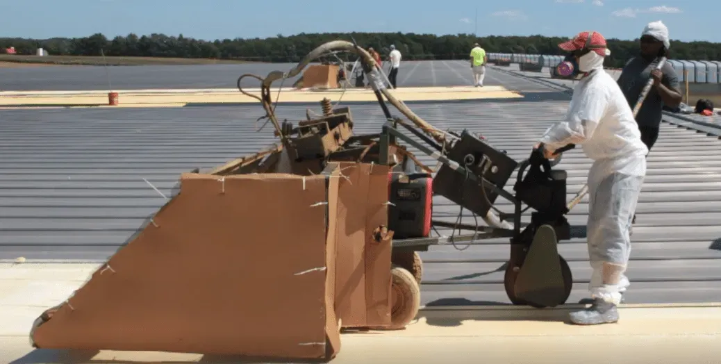 Workers in white protective suits handle a machine on a runway or tarmac.