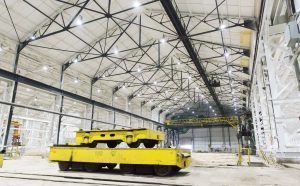 Yellow industrial vehicle in a large hangar with high metal truss ceiling