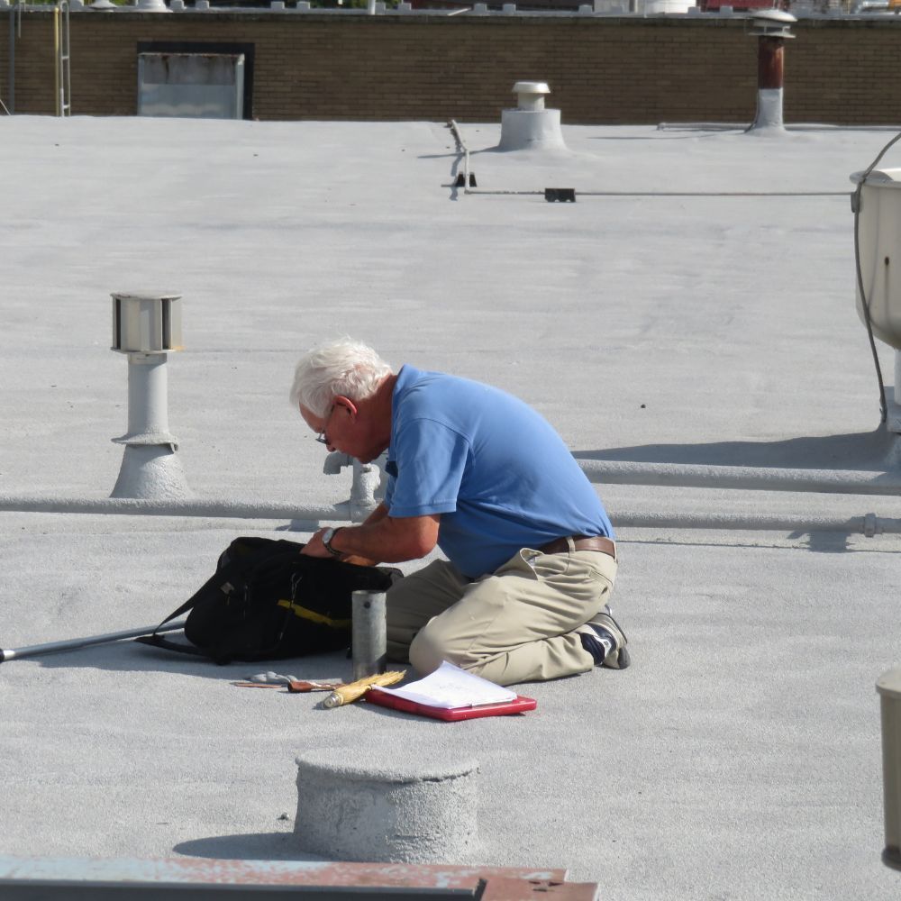 Worker kneeling on a rooftop, using tools next to an open black bag