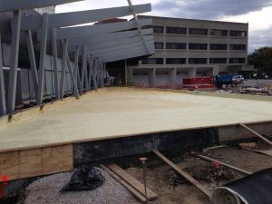 Damaged sidewalk and collapsed metal canopy beside a parking garage