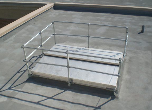 Metal platform cart with railings on a concrete rooftop or parking deck