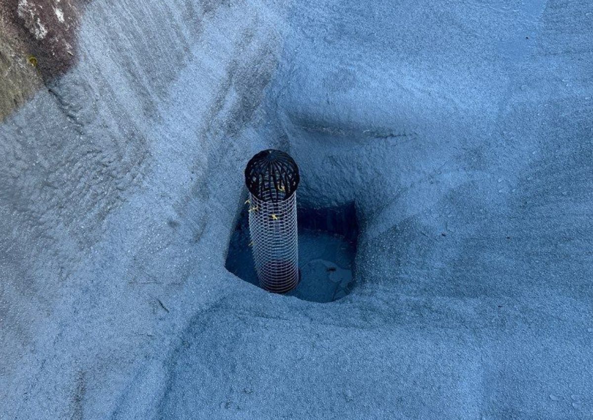 A blue icy trench with a small dark metal pipe protruding from a square opening.