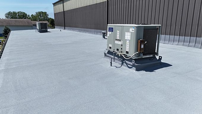 Rooftop HVAC units on a flat commercial roof beside a tall building.