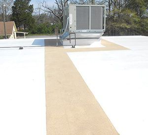 Rooftop HVAC unit on a flat white roof with tan walkway and a blue patch nearby.
