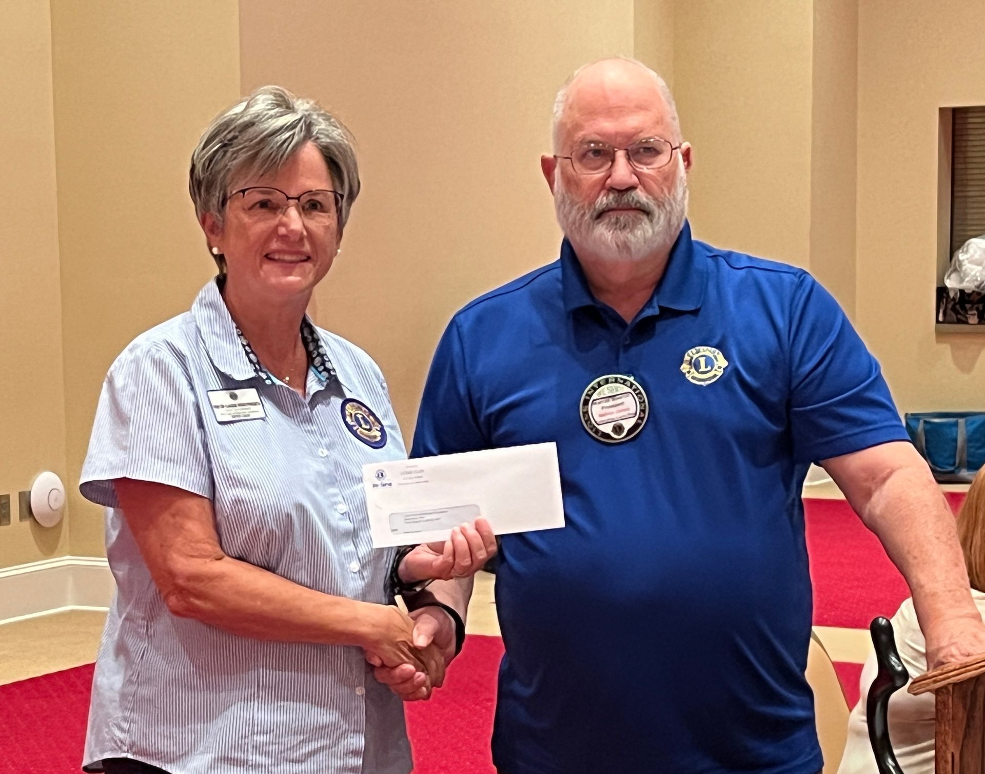 Woman in stripes hands check to man in blue shirt, indoors.