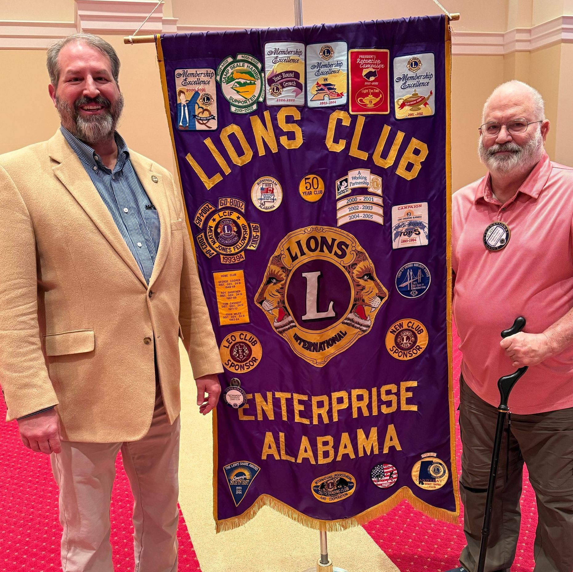 Two men stand with a purple Lions Club banner, 