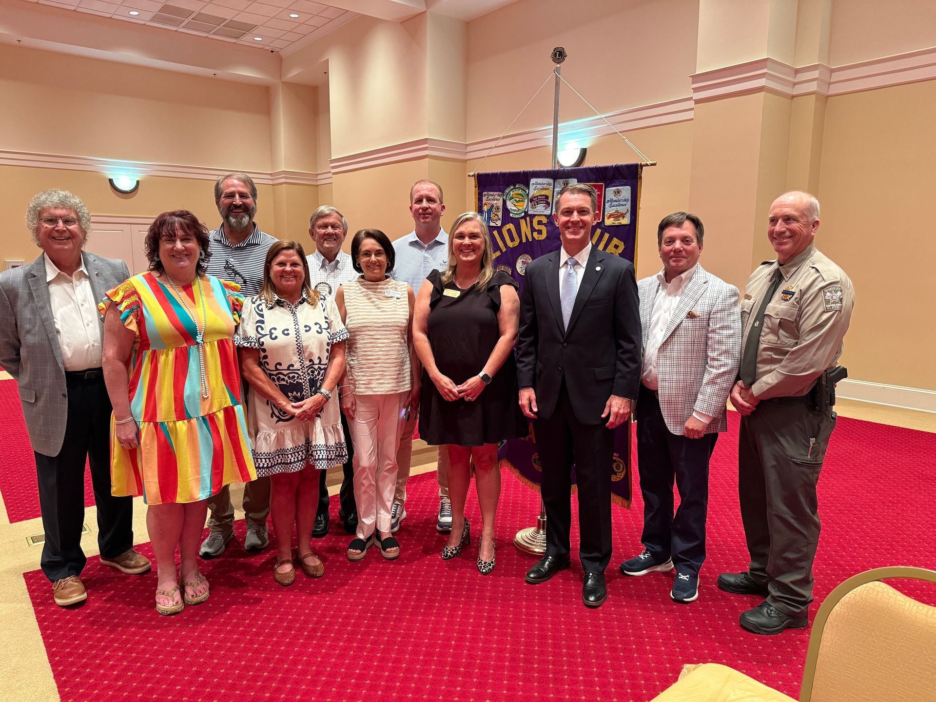 Group of people posing for a photo in a room with a Lions Club banner.