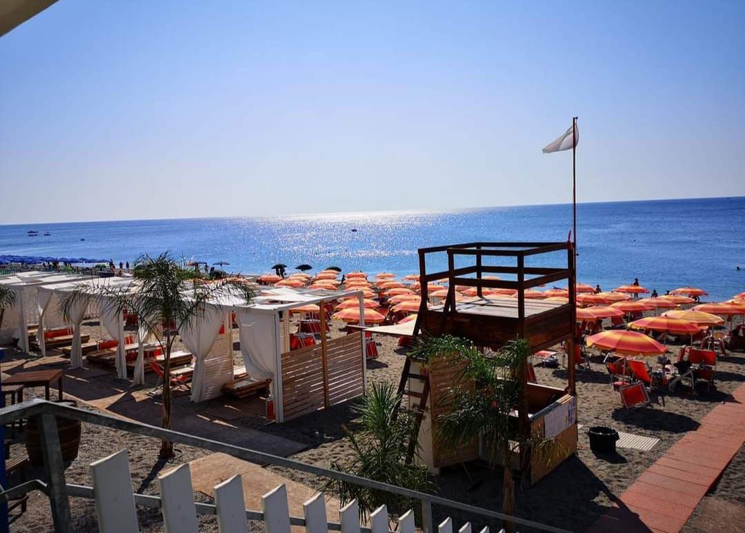 Una spiaggia con tanti ombrelloni e una torre di salvataggio.
