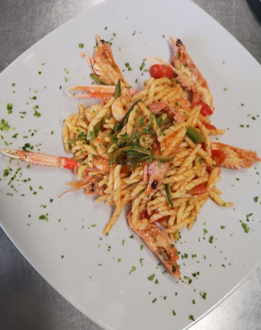 Un piatto di pasta con gamberi e verdure su un tavolo