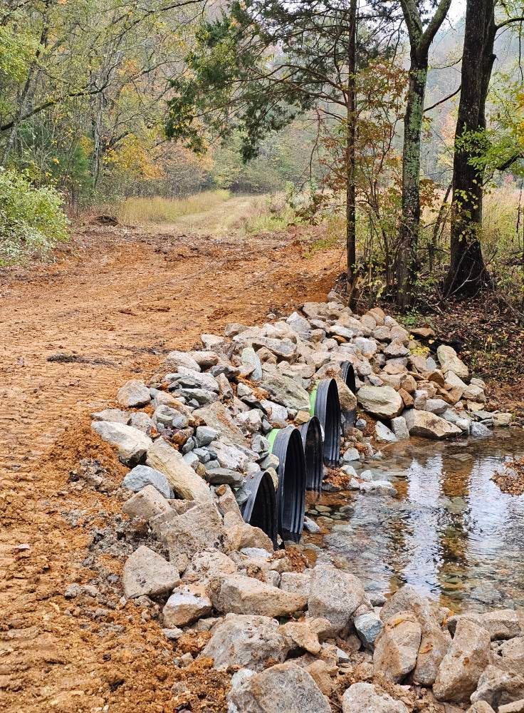 Rocky drainage ditch beside a dirt trail in a wooded autumn landscape