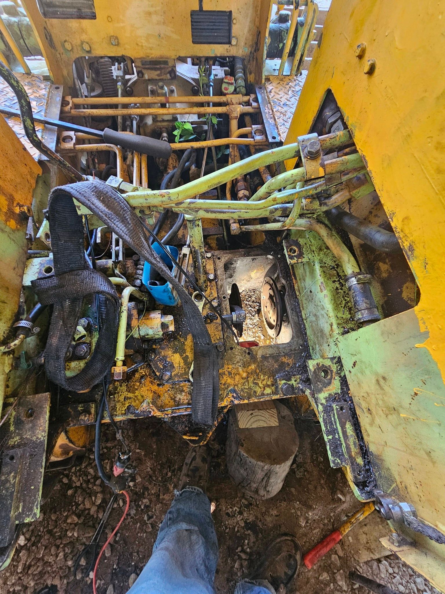 Rusty industrial machine interior with yellow panels, tangled hoses, and a person’s boot at the bottom.