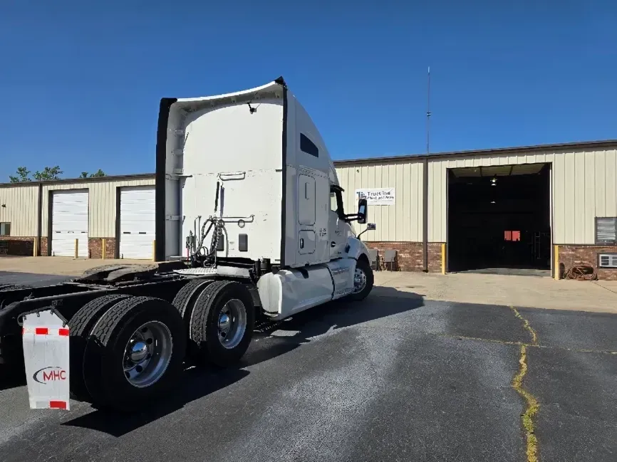 White semi-truck parked outside an open garage on a sunny day