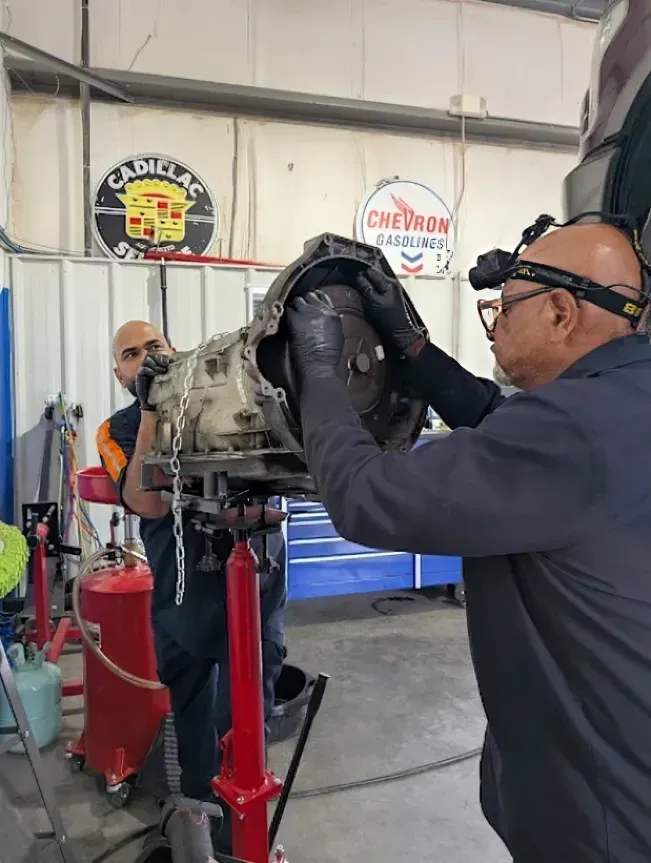 Mechanic inspecting a car engine on a red stand in a workshop