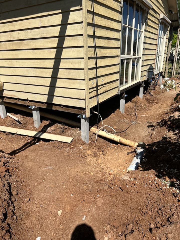A house is being built on stilts in the dirt.
