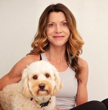 Woman with shoulder-length brown hair holding a fluffy white dog, both facing the camera against a light background