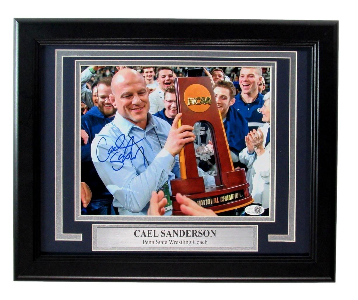 Cael Sanderson holding NCAA trophy, signed autograph, surrounded by teammates, framed.