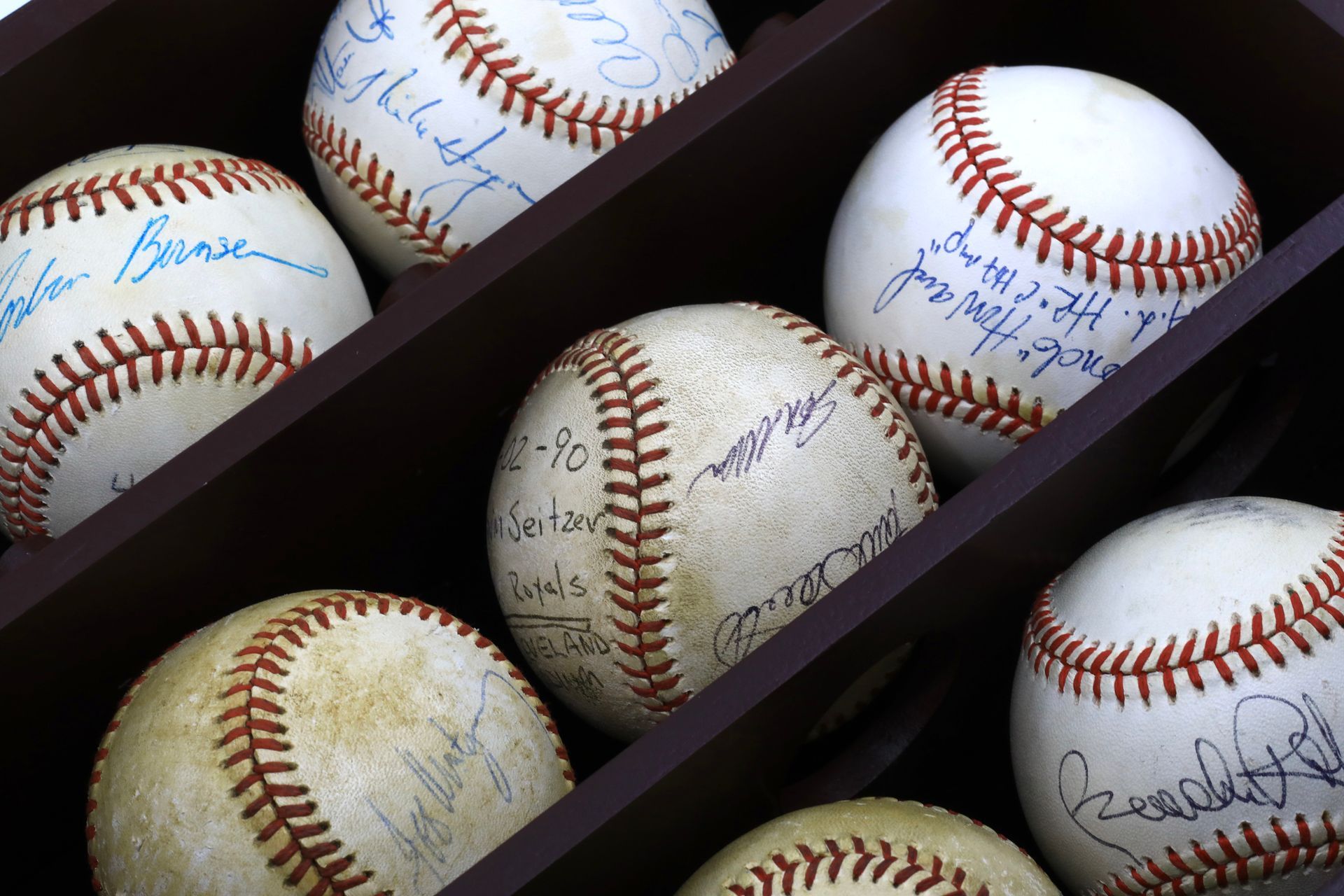 Signed baseballs displayed in wooden case as part of charity sports memorabilia auction.
