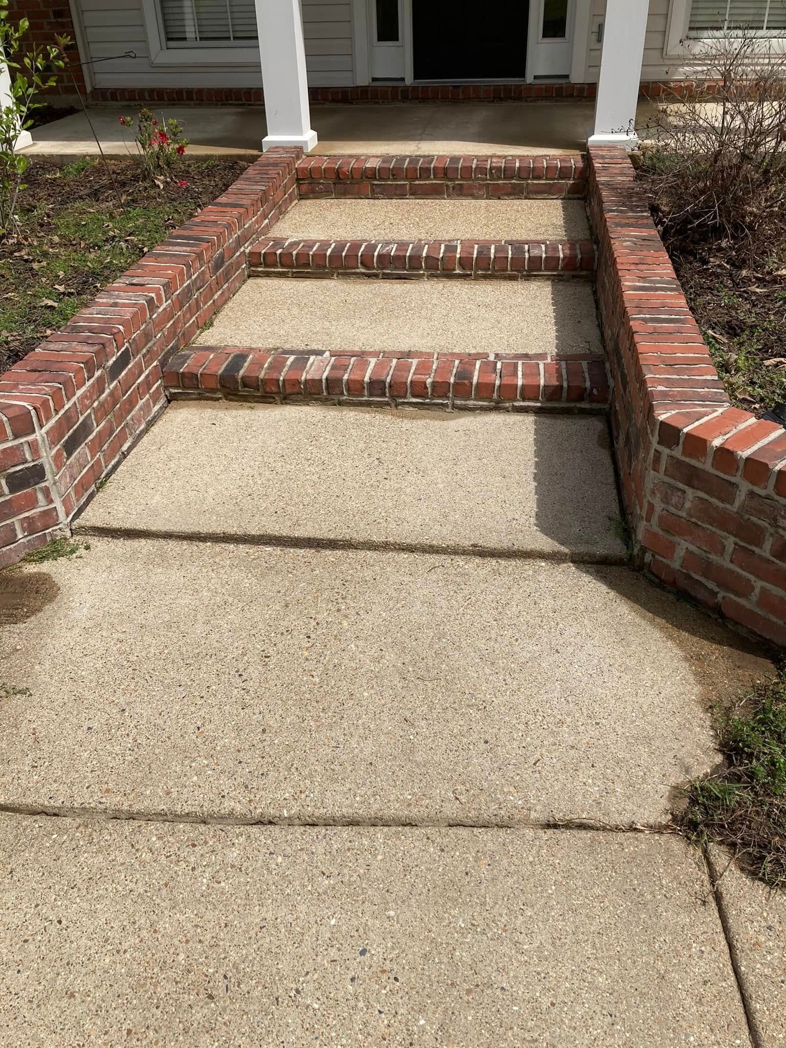 A front walkway with brick-edged concrete steps leading up to a house entrance.