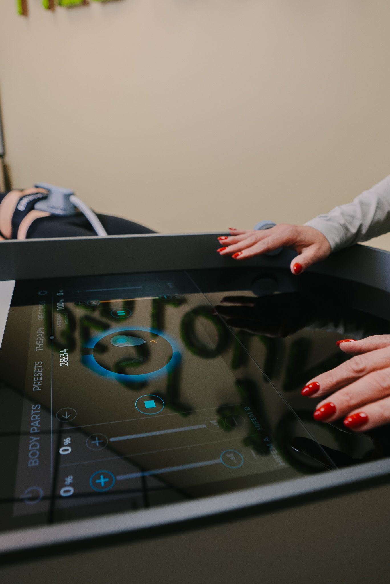 Hands using a touchscreen medical display with a teal interface in a clinical setting
