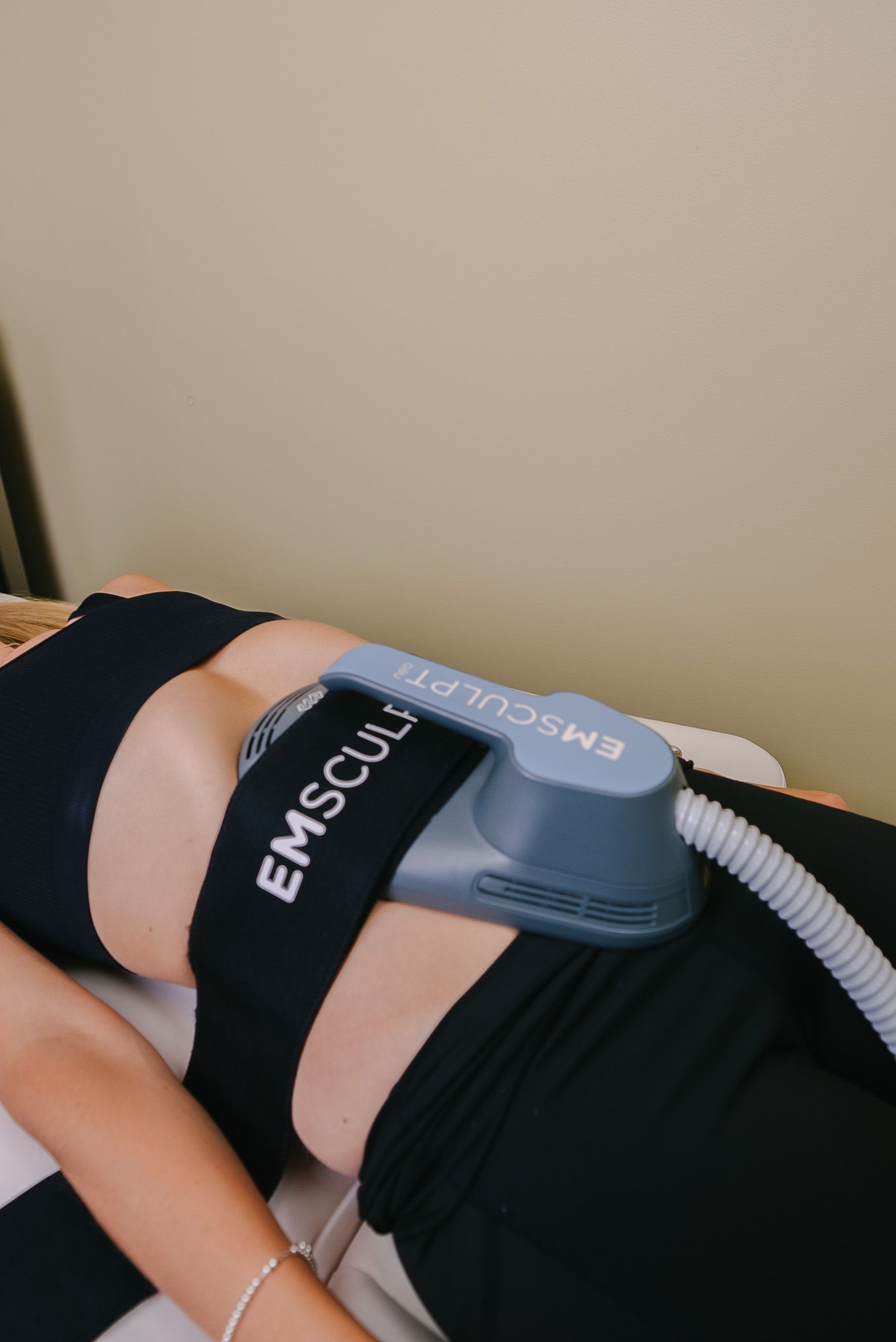 EMSculpt device strapped to a person’s waist during a body contouring treatment