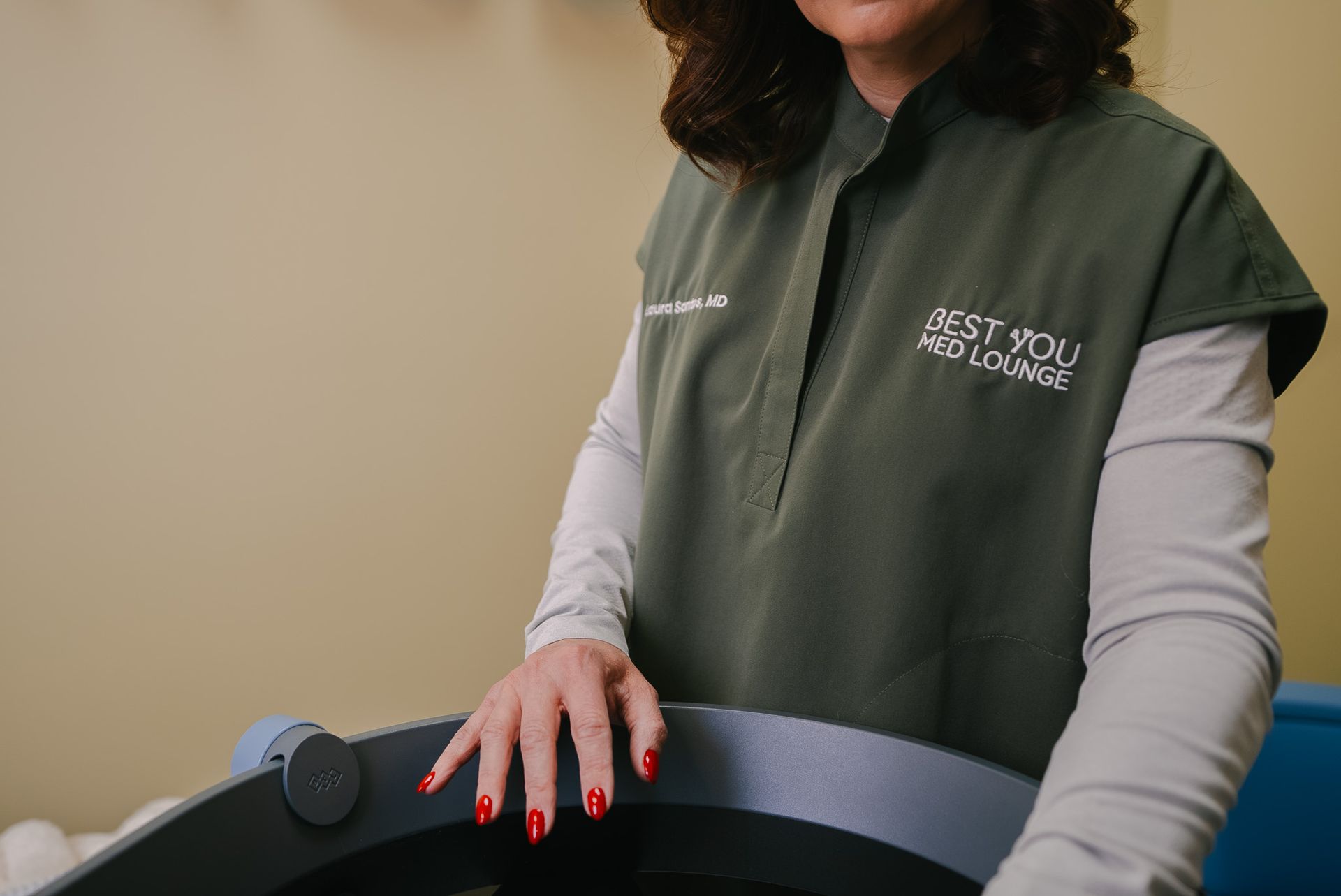 Woman in a green vest standing at a black counter in a clinic or office setting