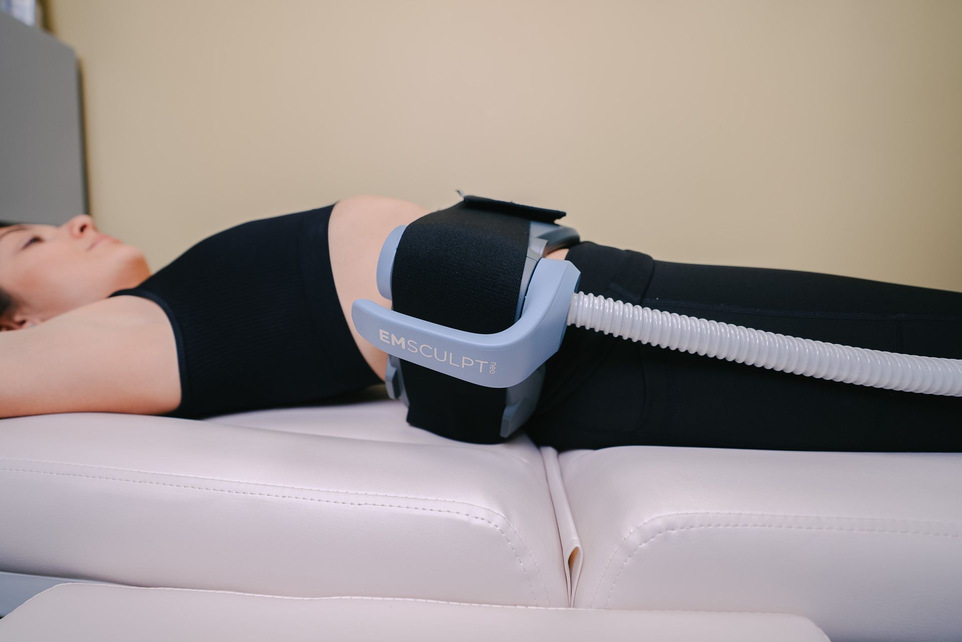 Person lying on a treatment table with a thigh compression device strapped around the leg