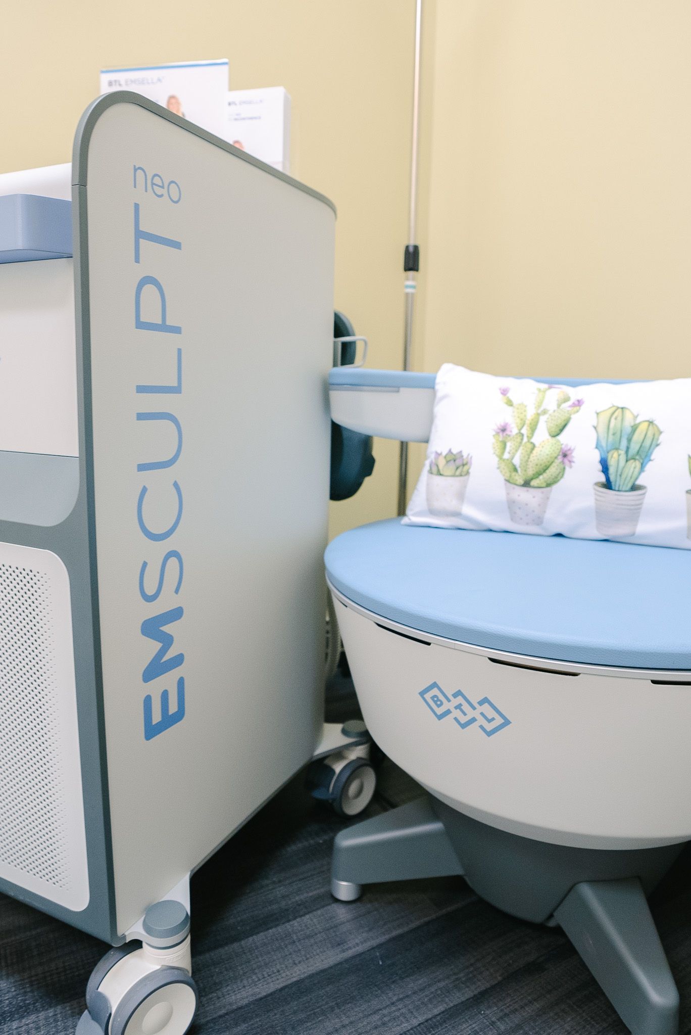 Photo of the EmSculpt NEO body contouring machine in a clinic, with a padded treatment seat and arm