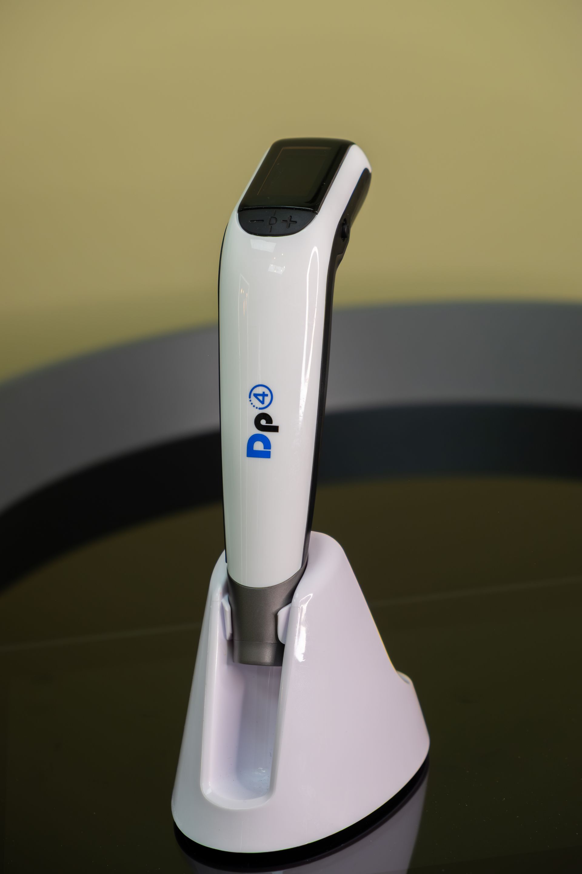 White and black handheld device on a charging dock against a dark background