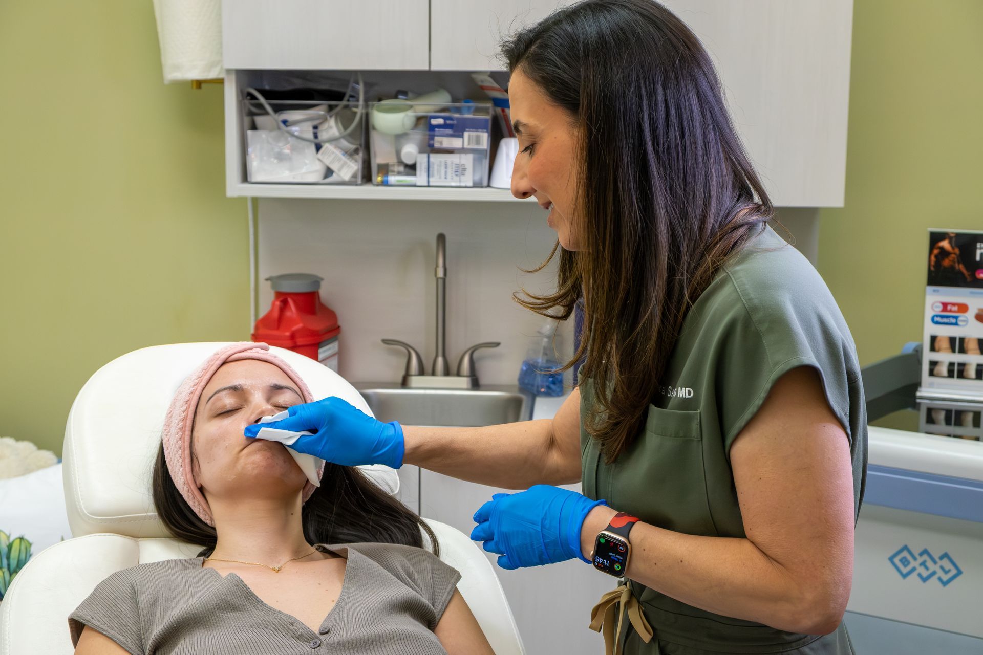 Dental clinician in blue gloves examining a patient’s mouth in a treatment room