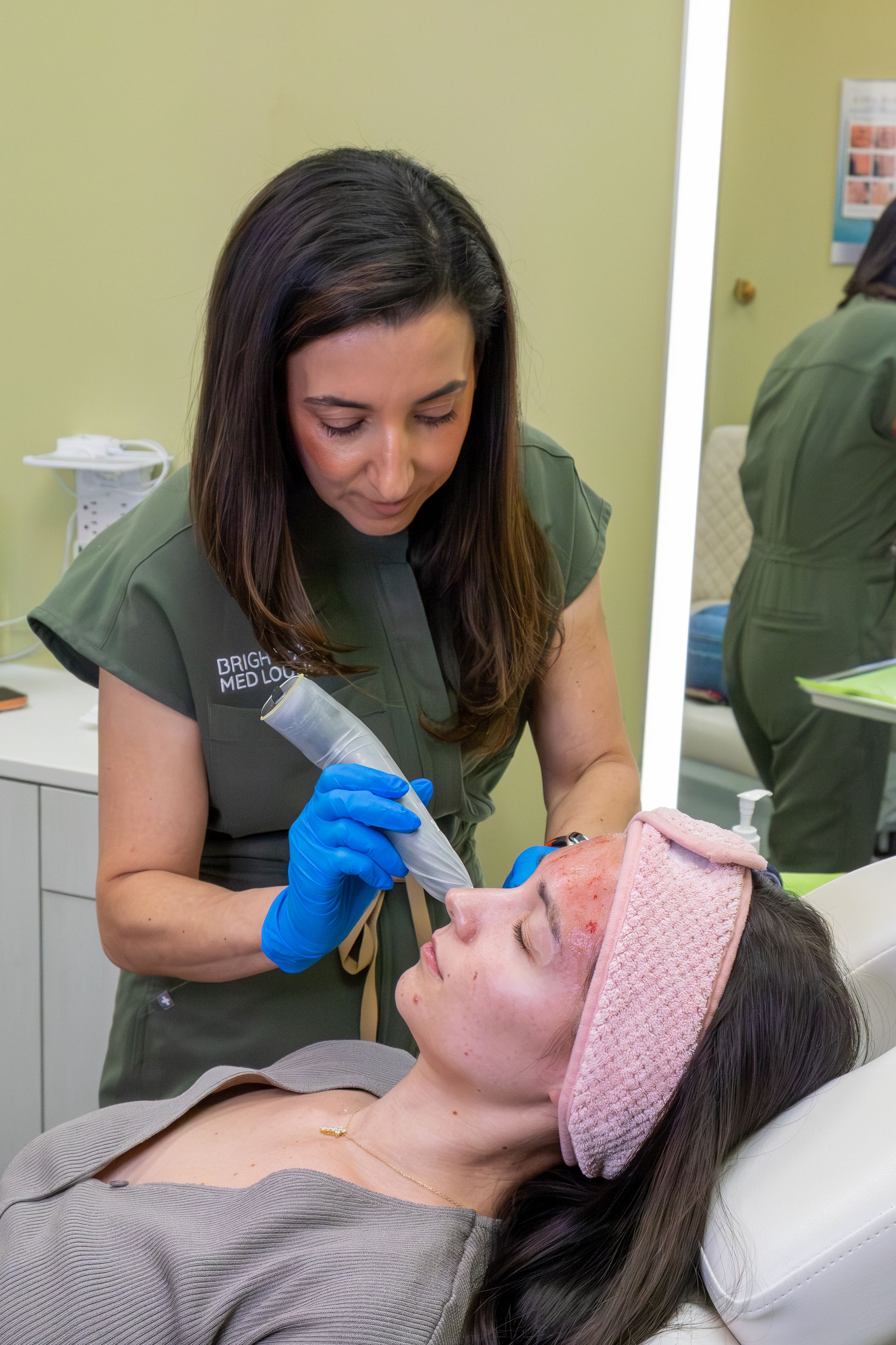 Technician performing a facial treatment on a client in a spa clinic room