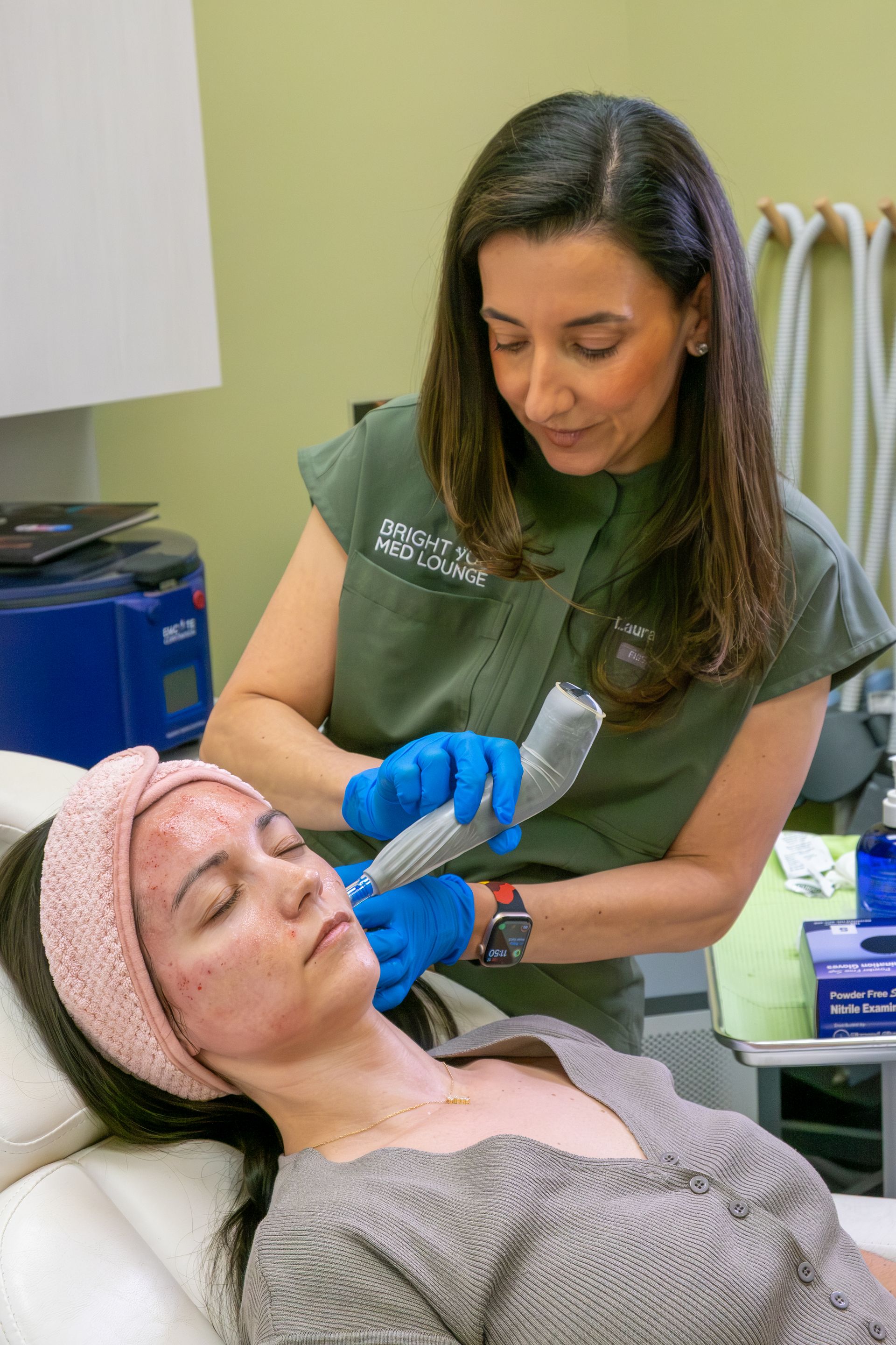 Esthetician applying a facial treatment to a reclining client in a spa treatment room