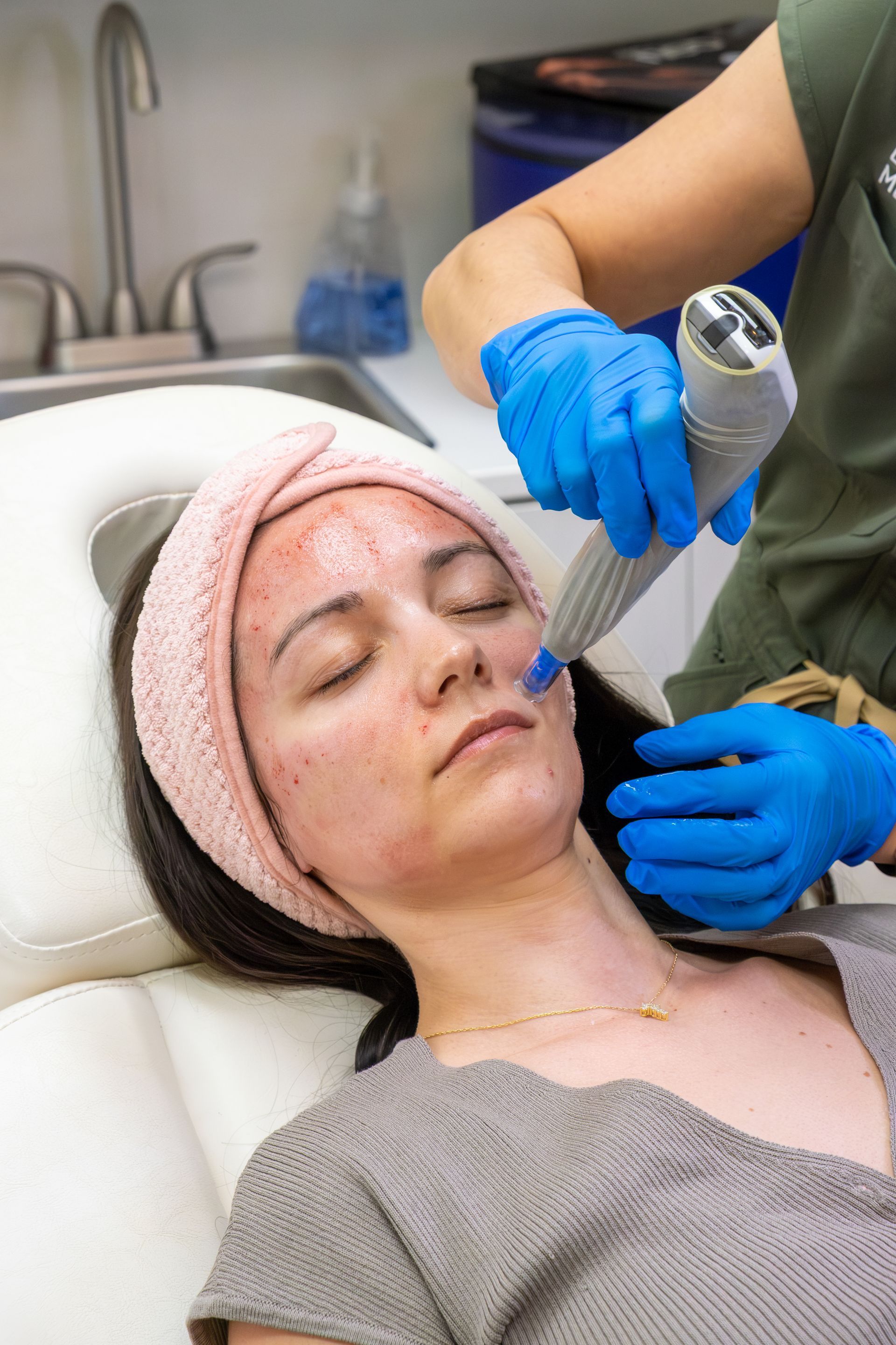 Cosmetic treatment applied to a woman’s face with a handheld device in a clinic chair