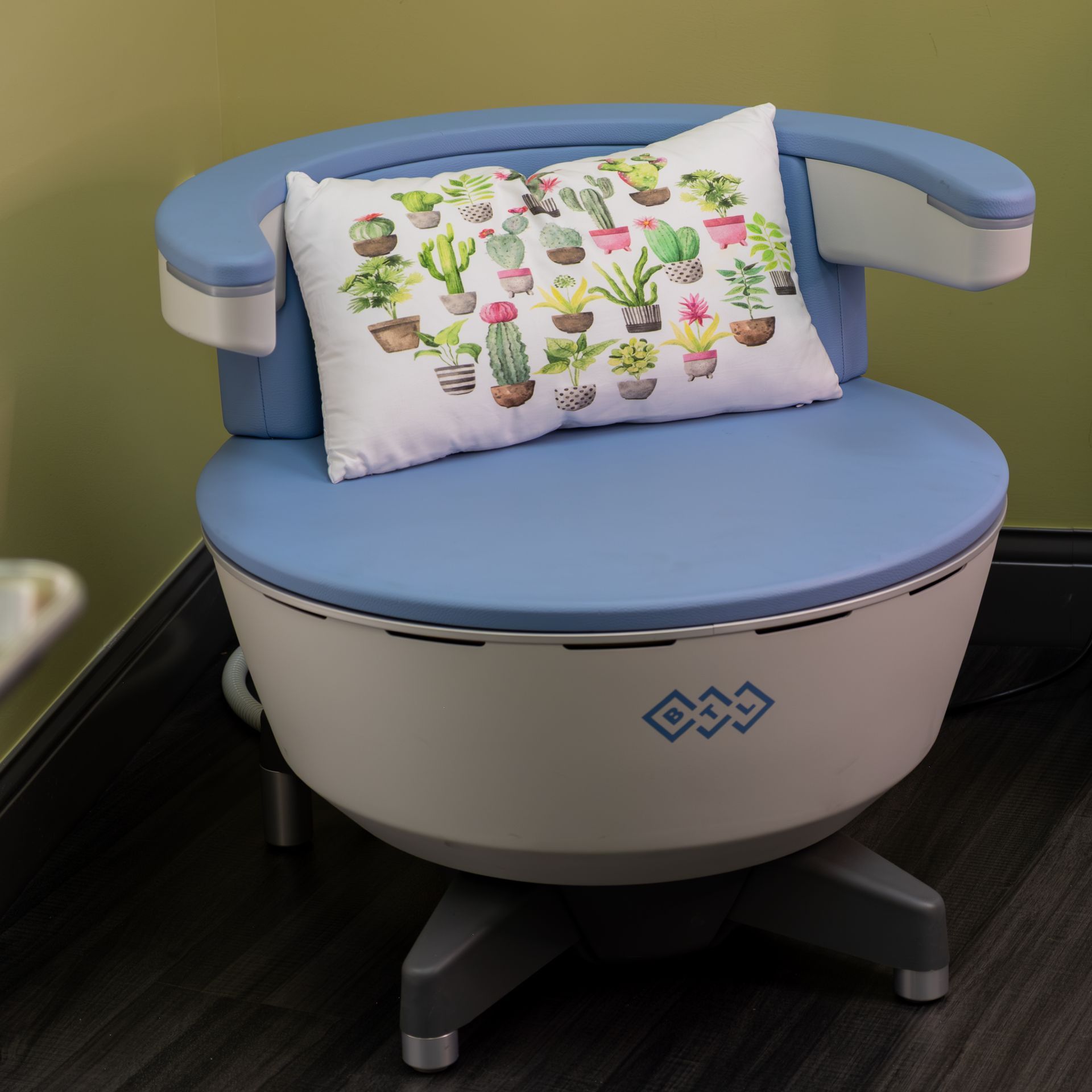 Blue cushioned chair with armrests and cactus-print pillow in a room