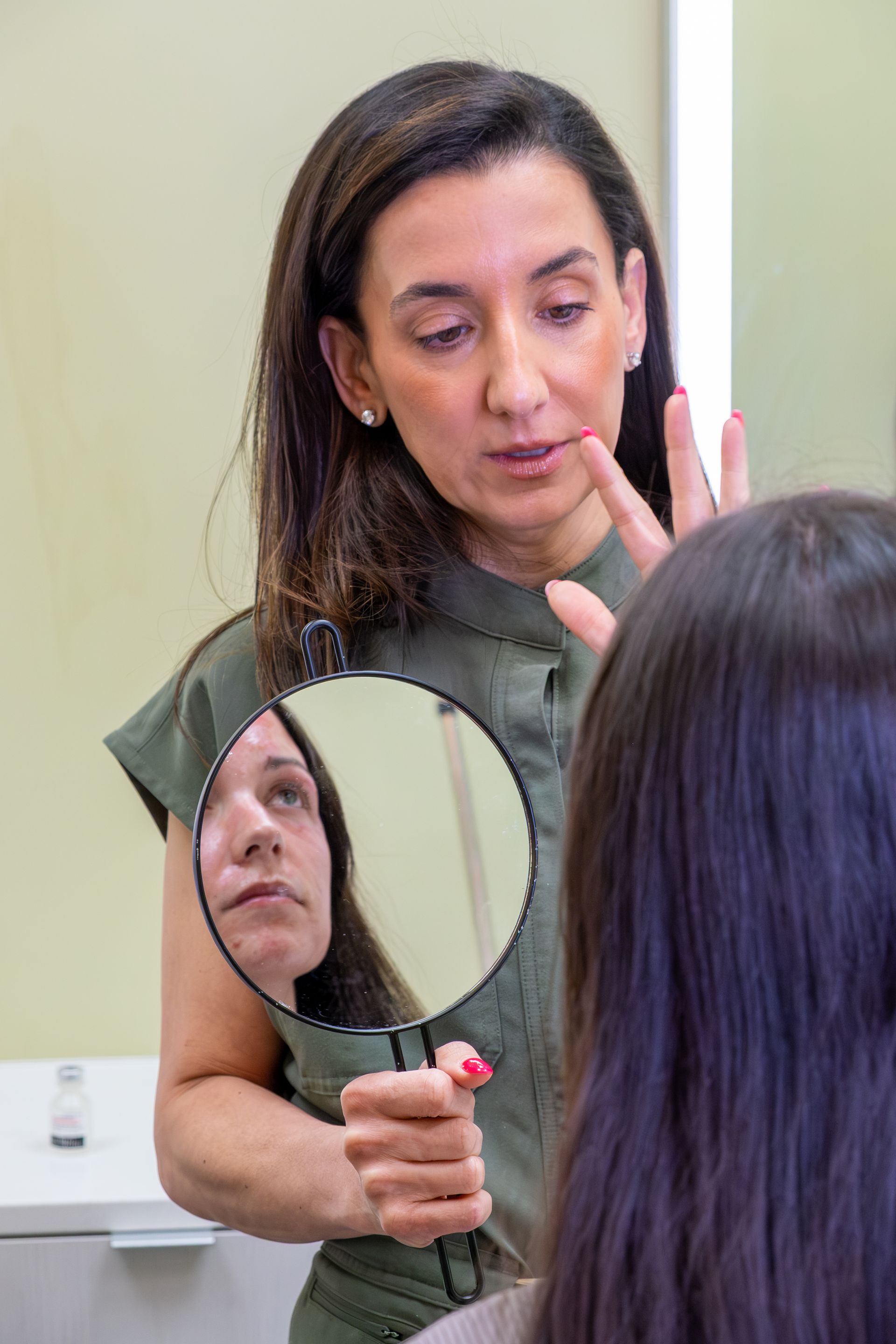 Stylist using a handheld mirror to show a client a hair color consultation at a salon