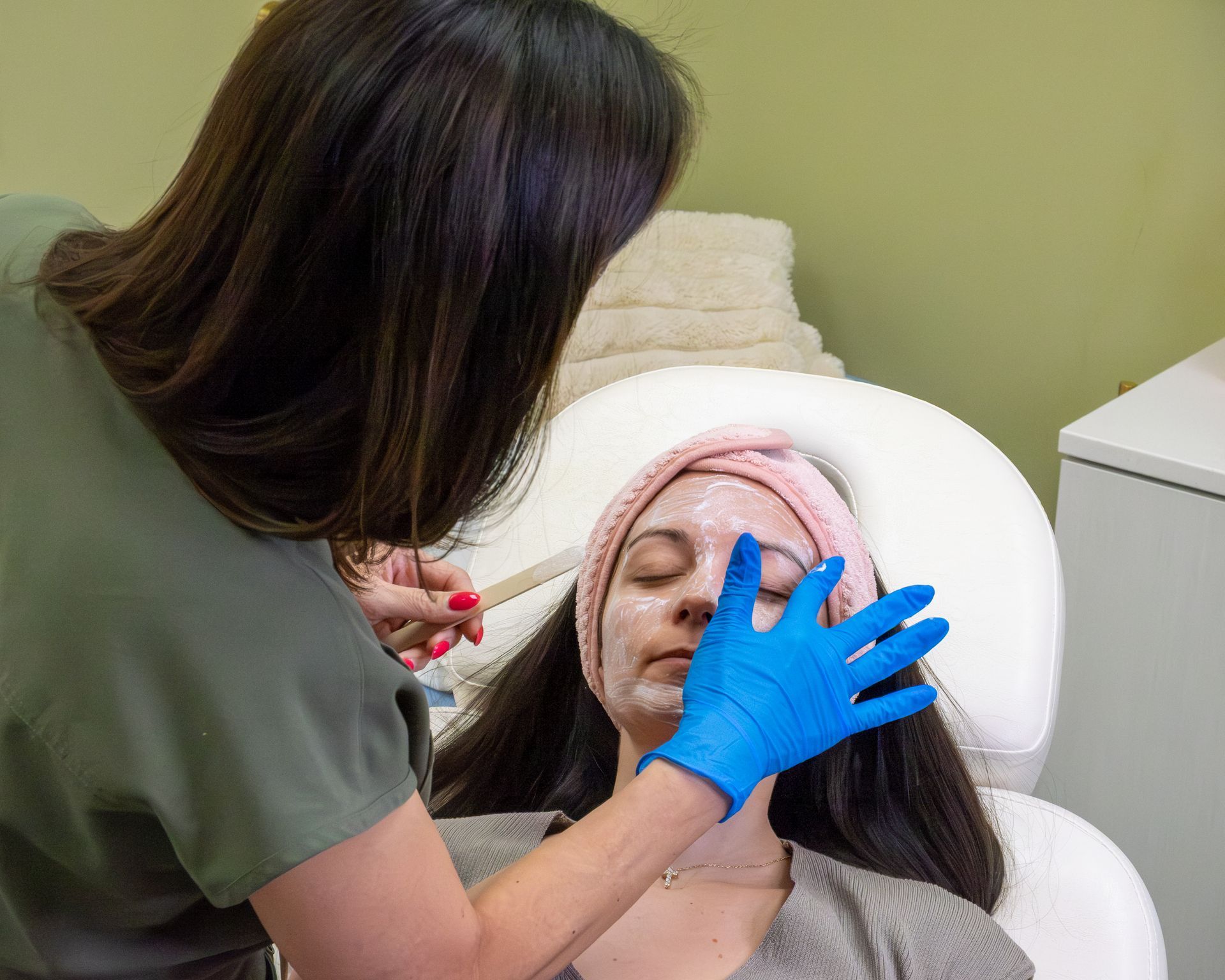 Clinician adjusts a patient’s face during a skincare treatment in a spa chair