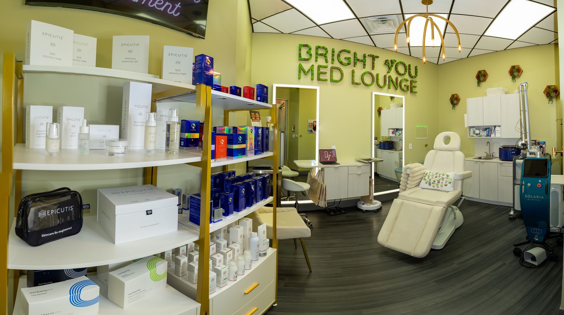 Interior of a Bright You Med Lounge, featuring skincare products on shelves, treatment chair, and bright lighting.