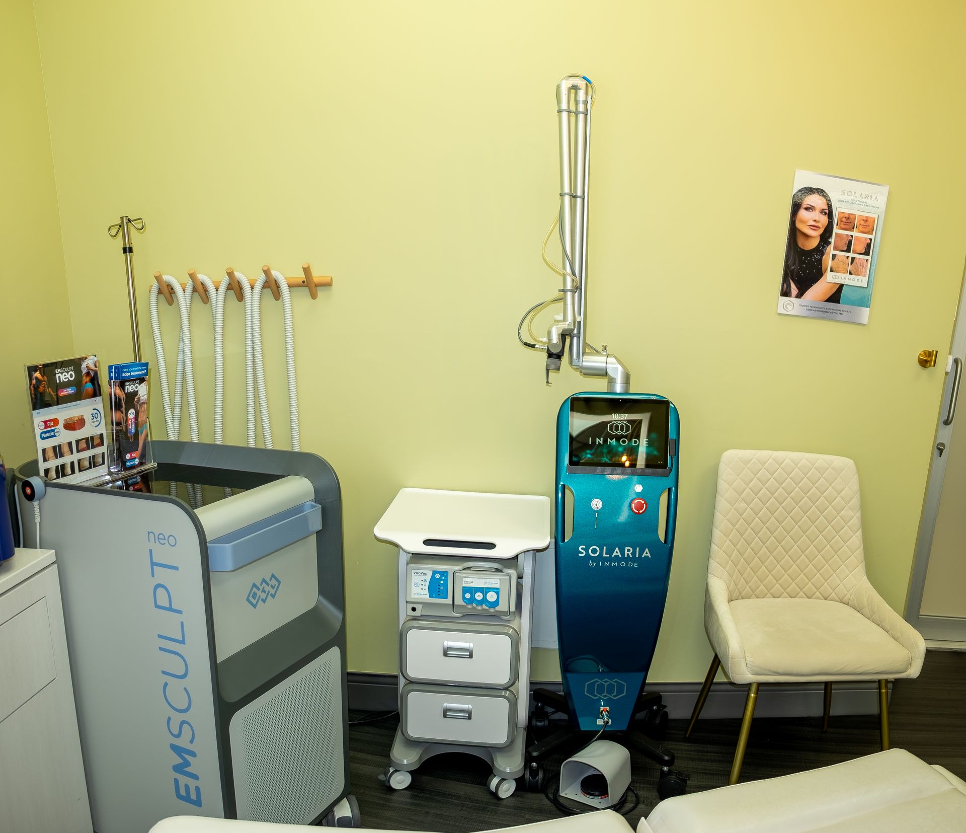 Medical spa room with laser device, chair, and Emsculpt machine.