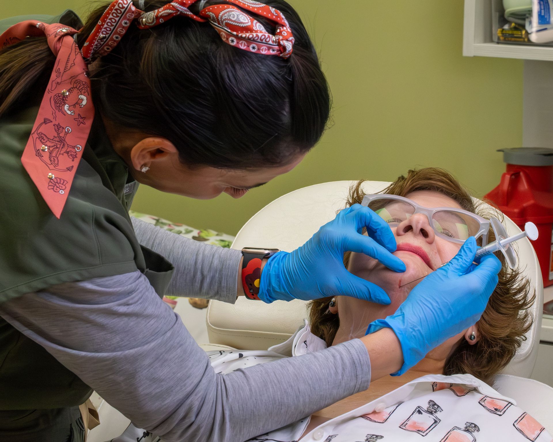 Dental hygienist cleaning a patient’s teeth in a clinic, wearing blue gloves and a face shield