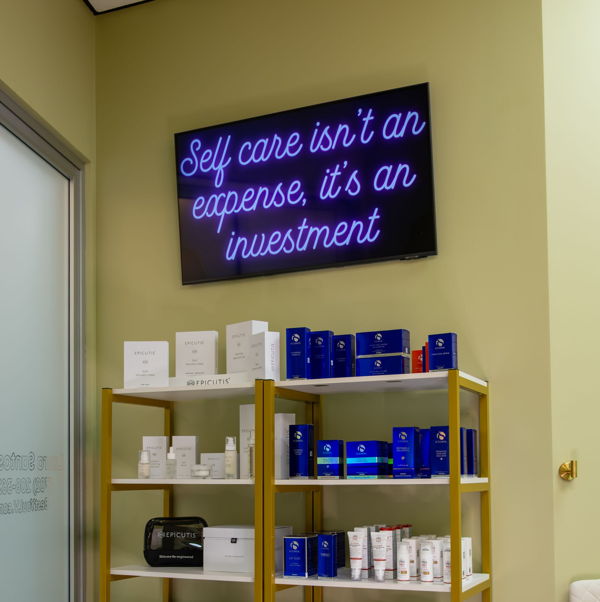 Neon sign reading “Self care isn’t an expense, it’s an investment” above a shelf of skincare products