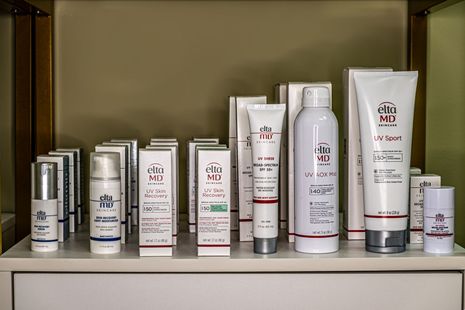 Assorted skincare products in white and silver bottles and tubes displayed on a shelf.