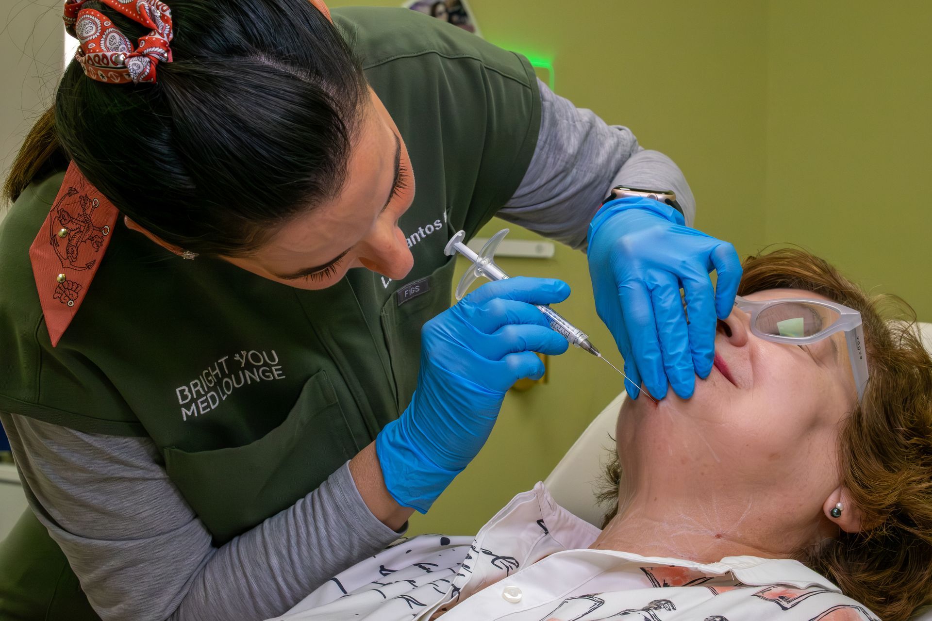 Dentist in blue gloves examines a patient’s teeth with tools in a treatment chair