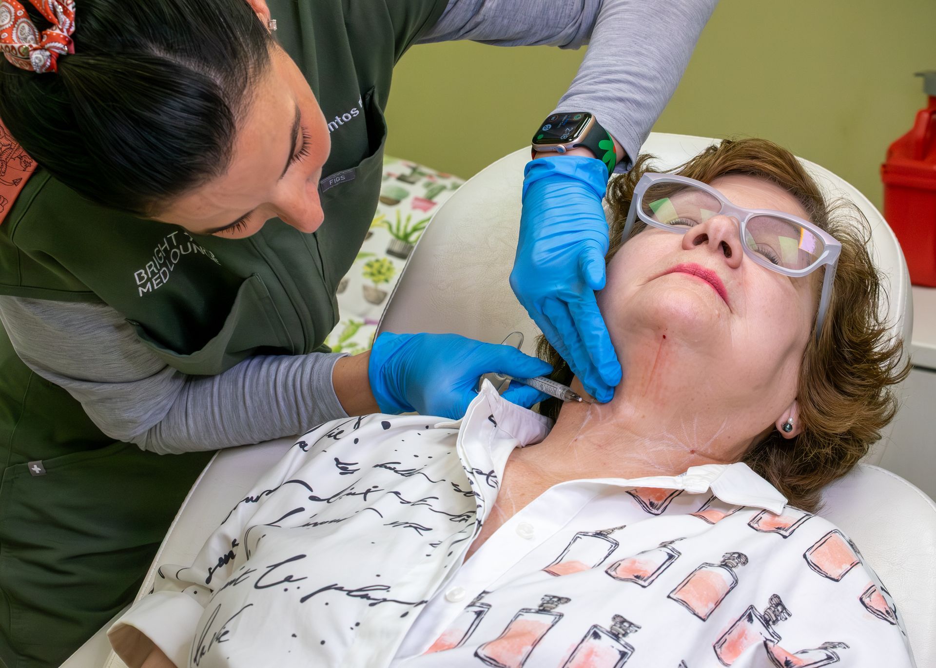 Clinician examining a patient's throat with gloved hands as the patient lies back in a dental chair