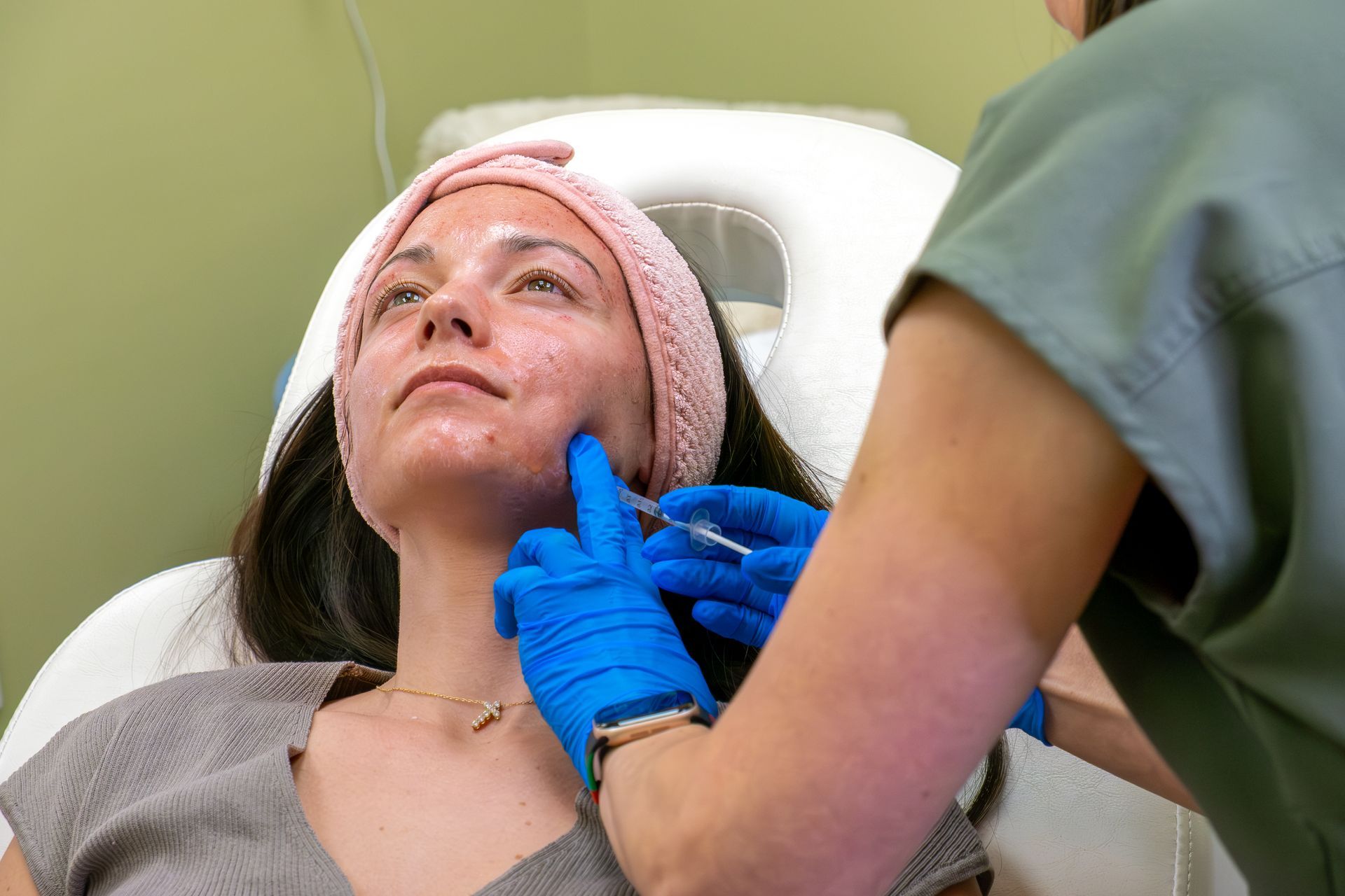 Patient receiving facial treatment with gloved clinician in a treatment chair